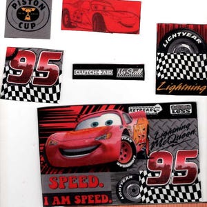 May include: A collection of Lightning McQueen themed stickers featuring the number 95, Piston Cup, and racing graphics. A wooden ruler measuring 5 inches is placed at the bottom to provide scale for the various rectangular and square adhesive decals.
