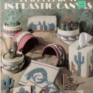May include: A craft instruction booklet titled Desert Designs in Plastic Canvas by Anne Fetzer, featuring various plastic canvas projects including cactus-themed tissue box covers, coasters, and decorative shapes in shades of blue, pink, and tan.
