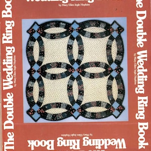 May include: A book titled "The Double Wedding Ring Book" by Mary Ellen Ingle Hopkins. The cover features a quilt design with interlocking rings in cream, black, blue, and red. The book's title is repeated on the cover.