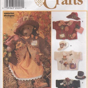 May include: Simplicity Crafts sewing pattern 7606 featuring Sunrise Designs by Jana Beus. The package displays a teddy bear wearing a brown hat, jacket, and orange checkered dress, alongside three small shirts with hats labeled A, B, and D.