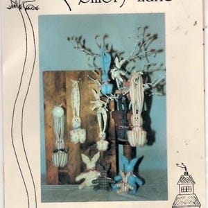 May include: A page featuring handmade "Hang Me" bunnies, door-knob bunnies, and hanging Easter or Christmas bunnies. The bunnies are in various colors and patterns, displayed on a wooden background and a tree branch. The text "Down Memory Lane" is at the top.