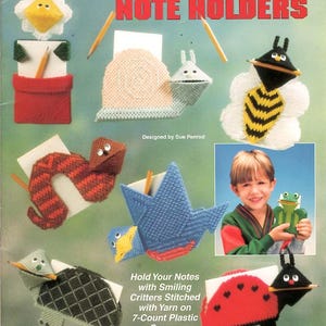 May include: A craft pattern booklet titled Handy Note Holders featuring various plastic canvas designs including a flower, snail, bee, snake, bird, turtle, and ladybug. The cover displays colorful stitched animal figures designed to hold notes and pencils.