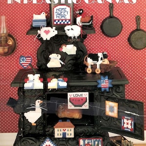 May include: A craft instruction leaflet titled More Country Magnets in Plastic Canvas featuring various small stitched designs including a Home Sweet Home sign, a cow, a goose, a watermelon slice with the word Love, and several heart-shaped motifs.
