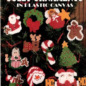 May include: A craft leaflet titled JOLLY ORNAMENTS IN PLASTIC CANVAS featuring 24 designs by Karen Wood. The cover displays various plastic canvas ornaments including a Santa, wreath, angel, gingerbread person, reindeer, candy cane, and tree.
