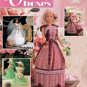 May include: A craft pattern booklet titled Fashion Doll Vanity Boxes by Annie's Attic. The cover features a blonde doll wearing a pink and burgundy chevron-patterned plastic canvas dress, with smaller inset photos showing dolls in white and green outfits.