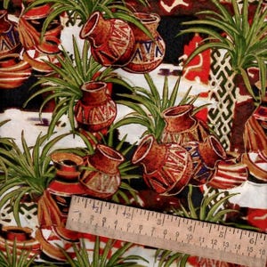 May include: A white fabric with a repeating pattern of green plants and brown pottery. The pottery has geometric designs in shades of brown, red, and blue. A wooden ruler is visible in the bottom of the image.