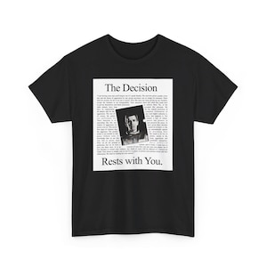 Puede incluir: Camiseta negra con un diseño gráfico cuadrado blanco. El diseño muestra el texto "The Decision" y "Rests with You." Dentro del cuadrado hay una imagen en blanco y negro de una persona y un bloque de texto.
