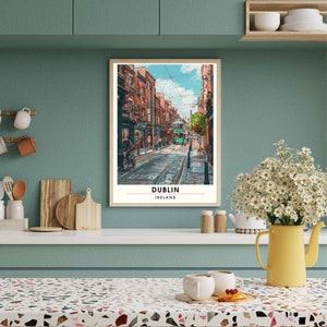 May include: A framed print showing a street scene in Dublin, Ireland. The image features a green tram on a cobbled street, flanked by red brick buildings. The print is labelled "DUBLIN IRELAND".