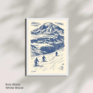 May include: A framed art print with a blue and cream illustration of a mountain scene with skiers. The print includes the text "Les Alpes" and "Bois Blanc White Wood".