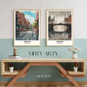 May include: Two framed art prints of Dublin, Ireland, displayed on a wooden shelf. One print shows a street scene with a green tram, the other a bridge over water. The prints are in a watercolour style. The text "Dublin Ireland" is at the bottom of each print.