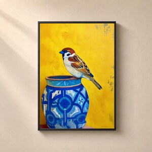 Peut inclure: Une impression d'art mural encadrée représentant un moineau brun et blanc perché sur le bord d'un vase en céramique à motifs bleus et blancs sur un fond jaune vif uni. L'œuvre est entourée d'un cadre rectangulaire noir fin.