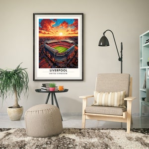 May include: A framed print of an aerial view of a soccer stadium with a sunset sky in the background. The stadium is surrounded by city buildings. The text "LIVERPOOL UNITED KINGDOM" is printed below the image.
