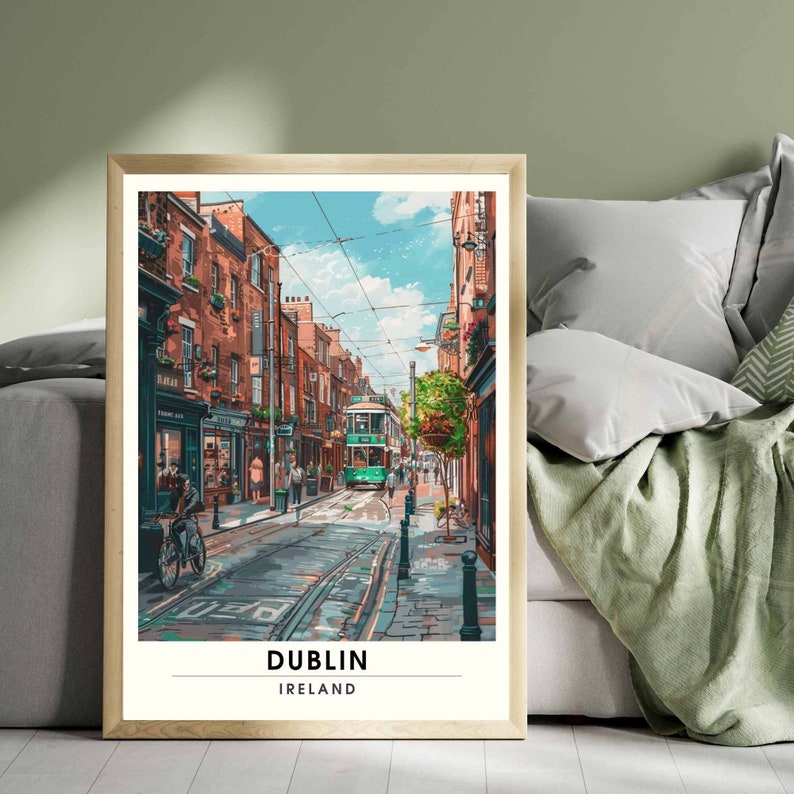 May include: A framed art print showing a Dublin street scene. The image features a green tram on a cobbled street, flanked by brick buildings. The sky is blue with clouds. The print is labelled "DUBLIN IRELAND" at the bottom.