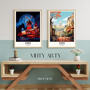 May include: Two framed art prints of Paris, France. The print on the left features a red windmill with a blue sky and stars. The print on the right features a street scene with a church in the background. Both prints have the word "PARIS" and "FRANCE" written below the image.