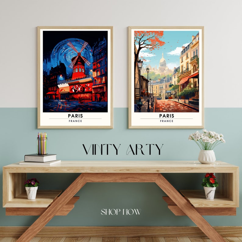 May include: Two framed art prints of Paris, France. The print on the left features a red windmill with a blue sky and stars. The print on the right features a street scene with a church in the background. Both prints have the word "PARIS" and "FRANCE" written below the image.