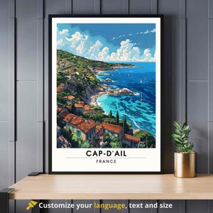May include: A framed art print depicting a coastal scene with turquoise water, sailboats, and buildings with red tile roofs. The sky is blue with fluffy white clouds. The text "CAP-D'AIL FRANCE" is at the bottom of the print.