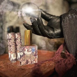 May include: Three small glass bottles with gold caps and a brown and gold label that says "Only Forever". The bottles are sitting on a wooden surface.