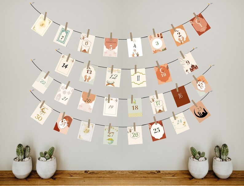 May include: A string of cards with numbers 1 through 30, hanging on a wall with clothespins. The cards are decorated with Islamic designs and the word "Ramadan".