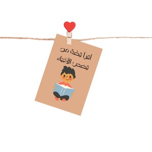 May include: A brown card with a red heart clothespin hanging from a string. The card has a cartoon illustration of a boy reading a book and the text "Aقرأ قصة من فصص الأنبياء" in Arabic.