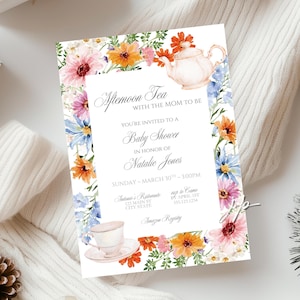 May include: Baby shower invitation with floral border. The invitation reads "Afternoon Tea with the Mom to Be" and includes details for the event, such as the date, time, and location. The design features watercolor flowers and a teapot.