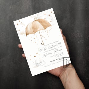 May include: A white baby shower invitation with a watercolor illustration of a brown umbrella with hearts falling from it. The text reads "Please join us for a Baby Sprinkle honoring the mom to be Melissa Russe. Main Street Cafe 123 Main St Chicago, IL Melissa by June 12th 123.123.1234 Melissa is registered at Target August 3rd 11:00 am"