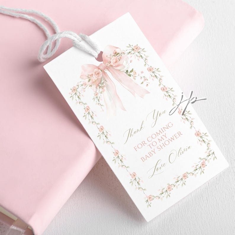 May include: A white gift tag with a pink bow and floral border. The tag reads "Thank You for Coming to My Baby Shower Love Olivia" in elegant script. A white string is attached for hanging.