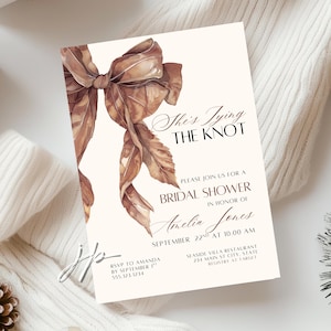 May include: A cream-coloured bridal shower invitation featuring a watercolour bow in brown and beige tones. The text reads "She's Tying the Knot", followed by event details. The invitation design is elegant and simple.