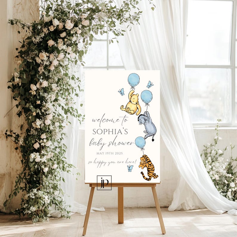 May include: A white welcome sign with Winnie the Pooh, Piglet, and Tigger characters holding blue balloons. The sign reads "Welcome to Sophia's Baby Shower, May 19th 2023, so happy you are here!"