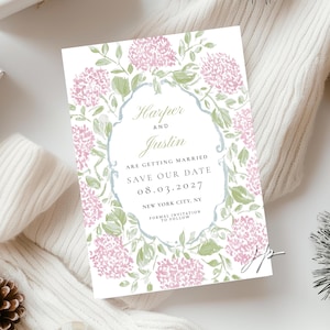 May include: A rectangular save the date card featuring a watercolor floral border of pink hydrangea blossoms and green leaves. The center text reads: Harper and Justin are getting married, save our date, 08.03.2027, New York City, NY, formal invitation to follow.