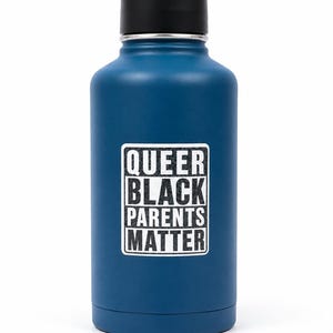 Pode incluir: Uma garrafa de água azul com tampa preta. A garrafa tem um adesivo retangular branco com as palavras "QUEER BLACK PARENTS MATTER" em negrito preto.