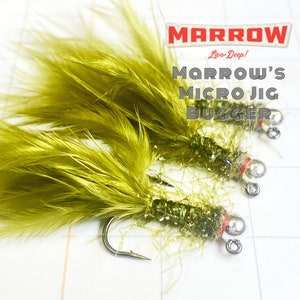 May include: Two olive green Micro Jig Bugger fishing lures with silver hooks and red accents. The lures have a fluffy feather design and are labeled "Marrow's Micro Jig Bugger" in white text with a red logo.