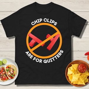 Puede incluir: Camiseta negra con un círculo blanco y clips para patatas fritas rojos tachados. El texto "Chip Clips Are For Quitters" está escrito alrededor del círculo.