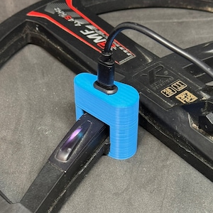 Könnte beinhalten: Ein blauer 3D-gedruckter Ladeständer für einen Metalldetektor. Der Ständer hat einen Schlitz für den Schaft des Detektors und einen USB-C-Anschluss zum Aufladen.