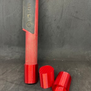 Op de afbeelding: Drie rode 3D-geprinte doppen voor een metaaldetector. De doppen hebben verschillende vormen en maten. De tekst "XP MI-6" is zichtbaar op de schacht van de metaaldetector.