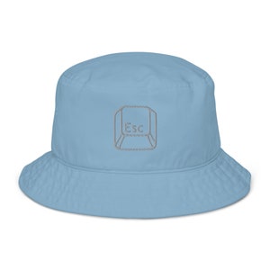 May include: A light blue bucket hat featuring an embroidered grey escape key graphic. The key is outlined in grey and has the word "Esc" in the centre.