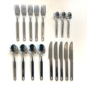 Könnte beinhalten: Ein Set aus Edelstahlbesteck, darunter Gabeln, Löffel und Messer. Die Gabeln und Messer haben einen silbernen Griff, während die Löffel einen schwarzen Griff haben. Das Besteck ist auf einer weißen Oberfläche angeordnet.