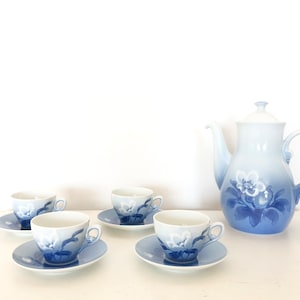 Könnte beinhalten: Hellblau-weißes Porzellan-Teeservice mit blauem Blumenmuster. Das Set besteht aus einer Teekanne, vier Tassen und Untertassen. Das florale Design verleiht dem Teeservice eine elegante Note.