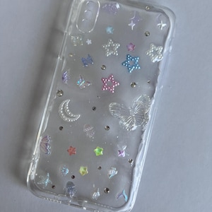 May include: A clear phone case decorated with a variety of colourful embellishments, including stars, butterflies, and seashells.