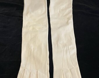 May include: A pair of long white leather gloves with a scalloped edge. The gloves are made of a soft, supple leather and have a classic design.