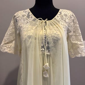 May include: A white lace and sheer nightgown with a tie at the neckline and a lace trim. The gown has a delicate floral pattern and is made of a soft, lightweight fabric.