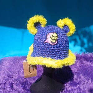 Blå, lila och gul virkad hinkhatt med tygmärke i festivalstil - redo att skickas