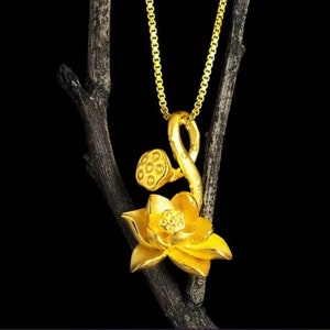 May include: A gold-tone necklace with a lotus flower pendant. The pendant features a detailed design of a lotus flower with a seed pod.