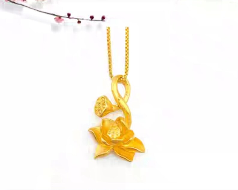 May include: A gold pendant necklace featuring a lotus flower design. The pendant is made of a single piece of gold and has a delicate, intricate design.