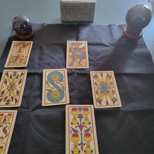 May include: Tarot card reading spread on a black cloth with two crystal balls. The cards are from a traditional Rider Waite deck and include the Magician, Eight of Pentacles, Two of Wands, Three of Cups, and the Knight of Wands.