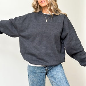 May include: A dark gray sweatshirt with a crew neck and long sleeves. The sweatshirt is made of a soft, comfortable fabric and has a relaxed fit.