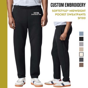 Può includere: Pantaloni della tuta neri con vita elastica e tasche laterali. I pantaloni della tuta hanno il testo "CUSTOM Embroidered Text" ricamato sulla gamba sinistra. Il testo "SOFTSTYLE MIDWEIGHT POCKET SWEATPANTS SF100" è stampato su uno sfondo giallo nell'angolo in alto a destra dell'immagine.