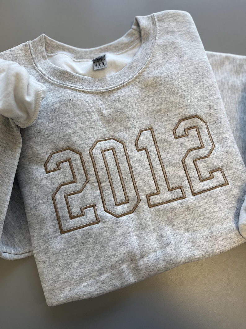 May include: A gray sweatshirt with the year 2012 embroidered in brown on the front.