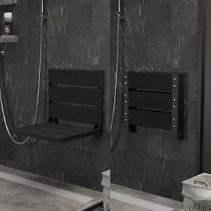 May include: Two black, wall-mounted shower seats with the word "GARDENIA" printed on them. One seat is folded down, and the other is folded up. The seats are mounted on a dark gray tiled wall.