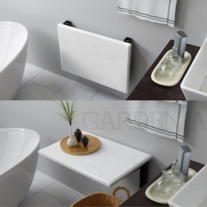 May include: A white marble folding table with black metal legs. The table is mounted to a wall and is in a bathroom setting. The table is folded up in the first image and unfolded in the second image.