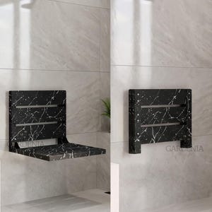 Peut inclure: Un siège de douche mural avec un motif de marbre noir et des veines blanches. Le siège est présenté en position ouverte horizontale et en position repliée verticale contre un mur carrelé. Le mot GARDENIA est imprimé sur le mur.